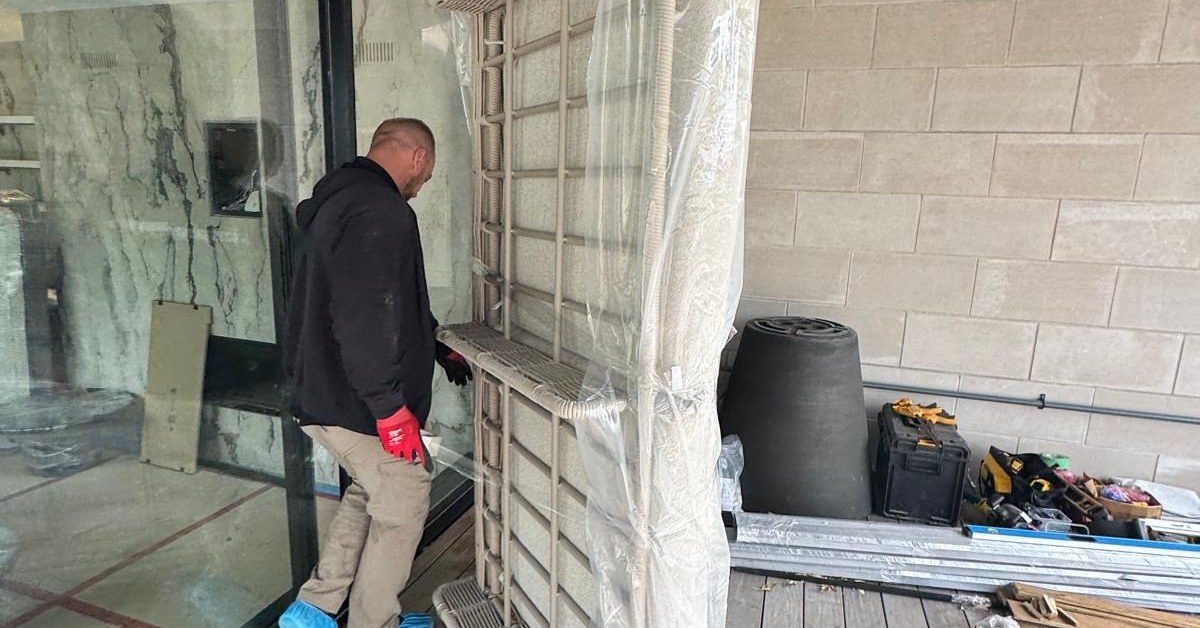 Grey Peacock movers carrying a wrapped sofa out of a Toronto home
